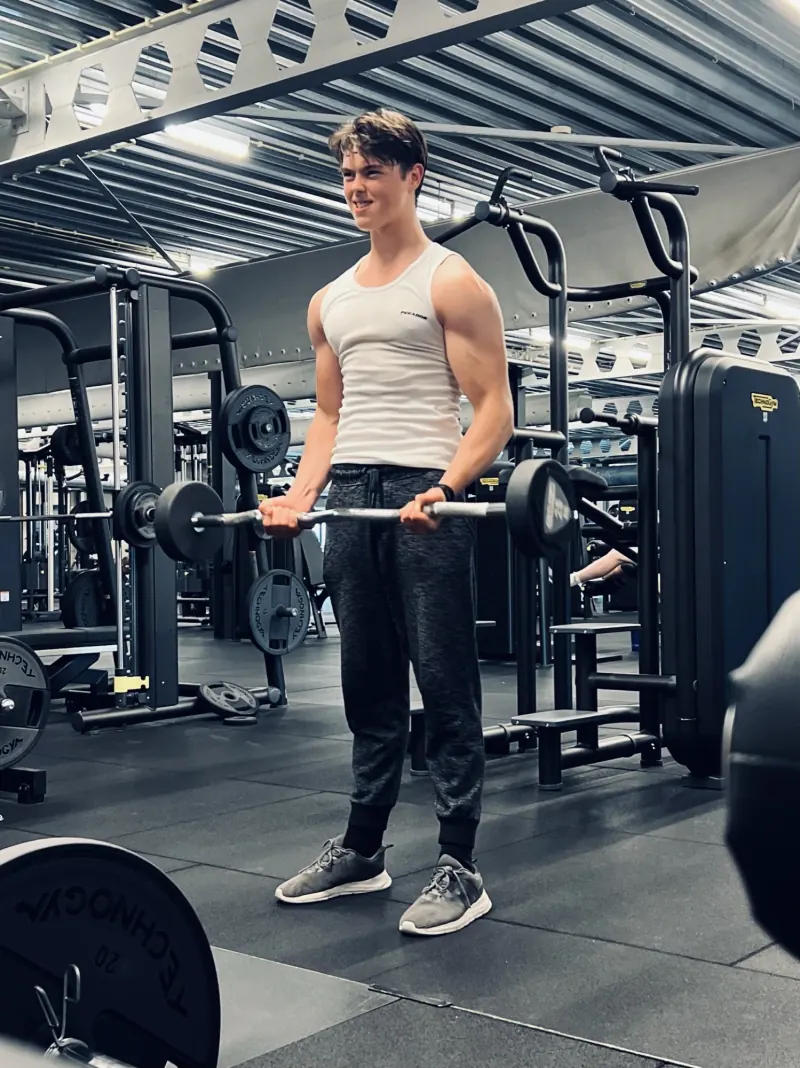 Klant traint met een barbell bij het rek